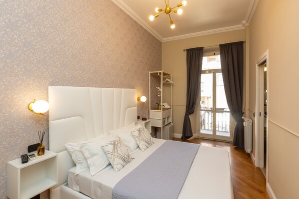 Habitación de hotel con una cama grande, mesitas de noche, un armario y vistas al exterior.