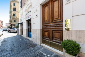 Un edificio con una puerta de madera grande, una planta verde pequeña y un letrero que dice 'Sticco Blu'.