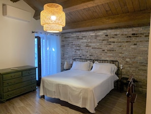 A bedroom with a brick wall, a bed with white bedding, a green dresser, and a hanging light fixture. - Al Borgo Da Rita (Città S Angelo)