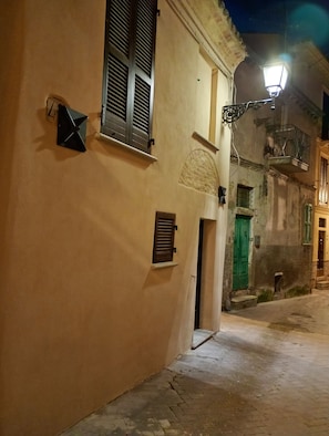 A narrow street with buildings on either side, a street lamp, and a door with a green shutter. - Al Borgo Da Rita (Città S Angelo)