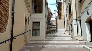A narrow street with a staircase leading to a building with a balcony.