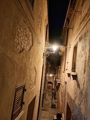 Un carreró estret amb parets de pedra i un fanal encès.