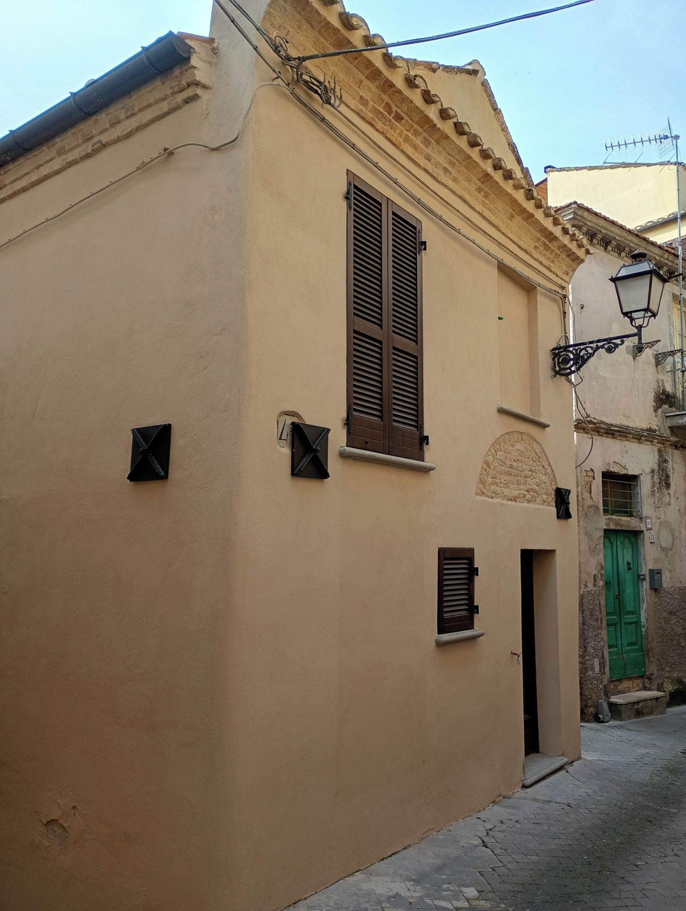 Un edificio con facciata beige, una porta principale e una porta verde sullo sfondo.