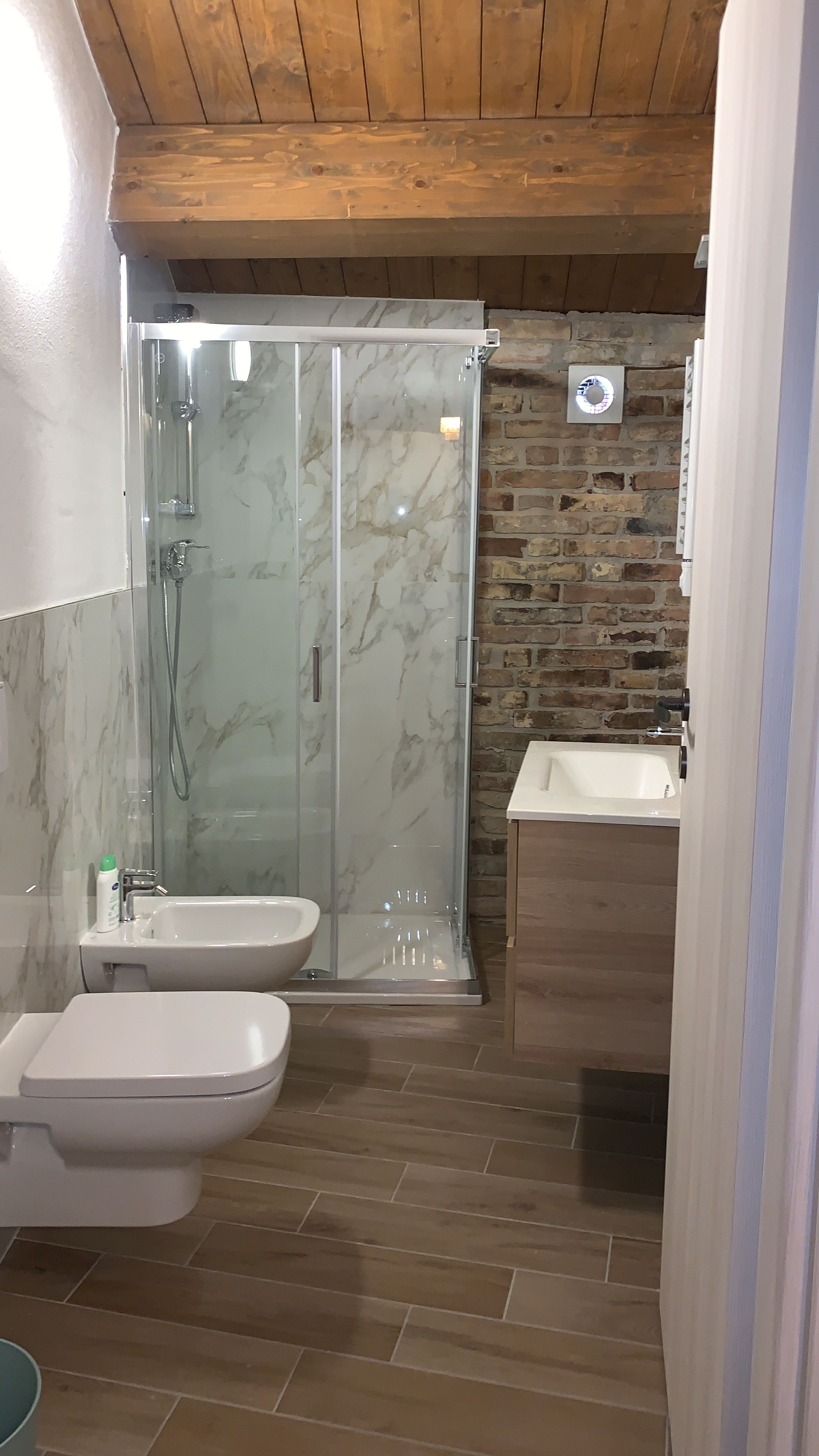 Un bagno con doccia vetrata, lavandino e WC.