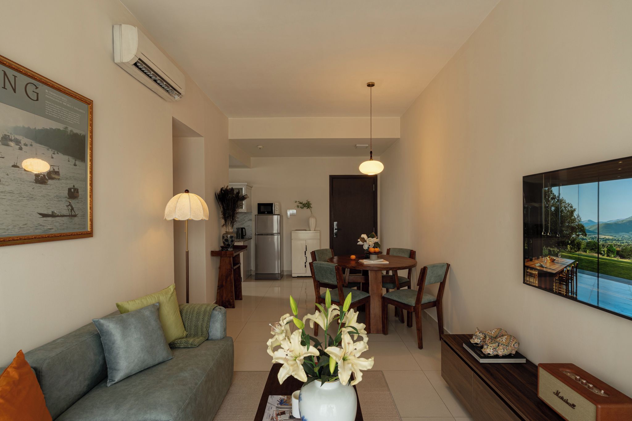 Un soggiorno moderno con un divano, un tavolo da pranzo con sedie, una zona cucina e un'ampia finestra con vista.