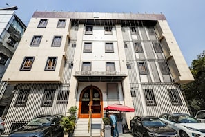 A multi-story hotel with a prominent entrance, a red awning, and a series of windows. - Sanca International Patel Nagar New Delhi (New Delhi)