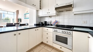 A modern kitchen with white cabinets, a black countertop, and a built-in oven. - 3-Bedroom Beachfront Apartment with Ocean Views & Pool – Umhlanga Rocks (uMhlanga)