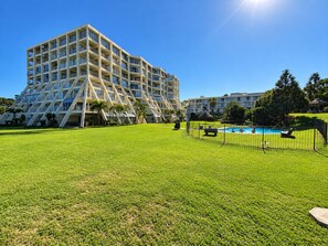 A modern hotel with a unique triangular design, a swimming pool, and a well-maintained lawn. - 3-Bedroom Beachfront Apartment with Ocean Views & Pool – Umhlanga Rocks (uMhlanga)