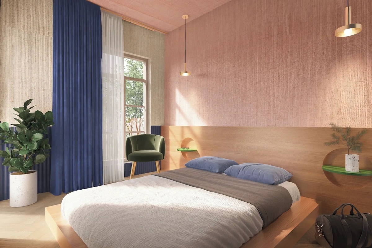 Quarto com cama, cadeira, mesa de cabeceira, luminária e planta em vaso.