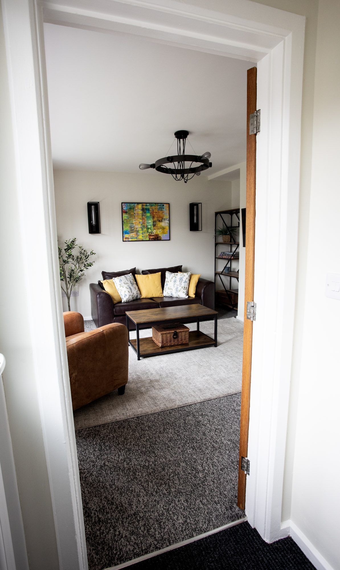 A living room with a brown leather sofa, a coffee table, and a chandelier.