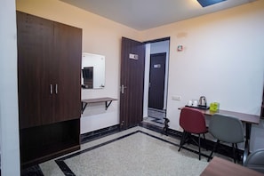 Habitació d'hotel amb escriptori, cadires, armari, mirall i una porta que dona a una altra habitació.