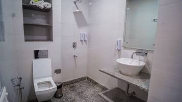 Un baño pequeño con inodoro, lavamanos, ducha y espejo.