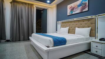 Un dormitorio moderno con una cama grande, una mesita de noche y un cuadro en la pared.