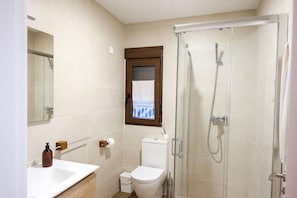 Une salle de bain avec douche, toilettes et lavabo.