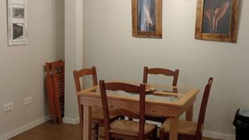 Een eetruimte met een houten tafel en stoelen, een hanglamp en twee ingelijste foto’s aan de muur.