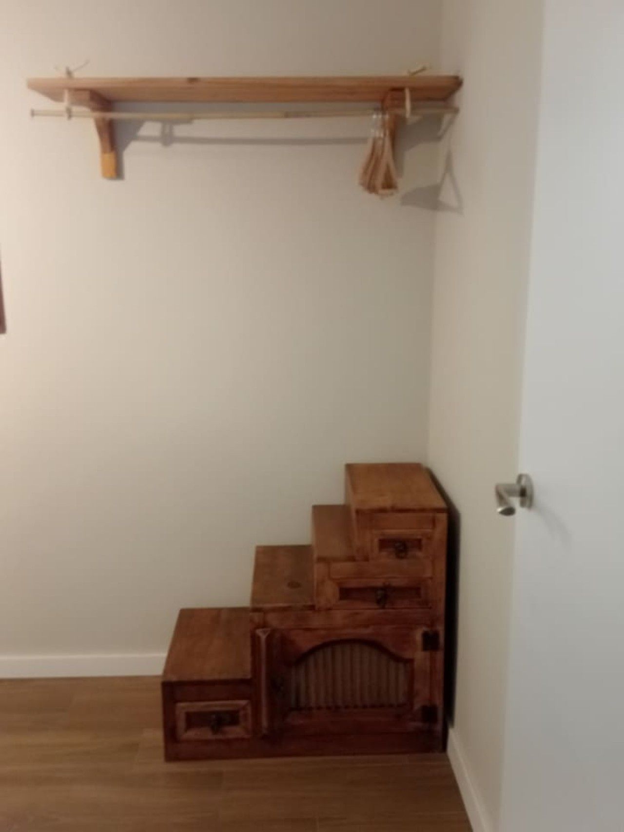Un coin de pièce avec un banc en bois et une étagère en bois adossée au mur.