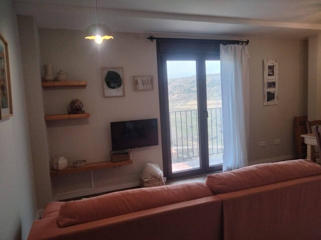 A living room with a sofa, a television, and a balcony with a view.