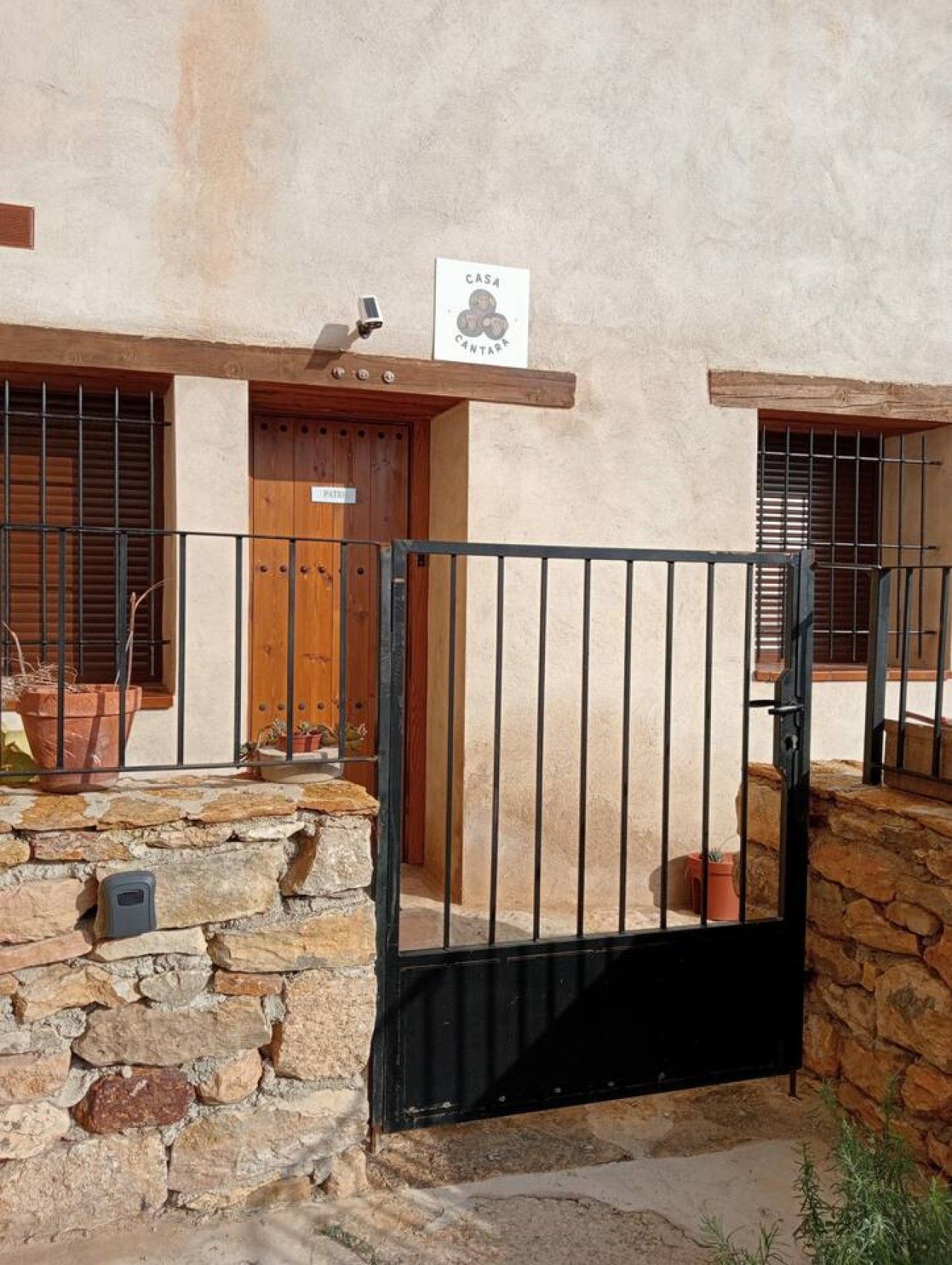 A rustic building with a stone wall, a wooden door, and a metal gate.