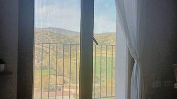 Ein Zimmer mit einem großen Fenster, einem dunklen Holzboden und einem Korb auf der linken Seite.