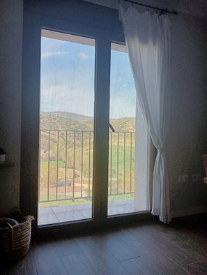 Ein Zimmer mit einem großen Fenster, einem dunklen Holzboden und einem Korb auf der linken Seite.