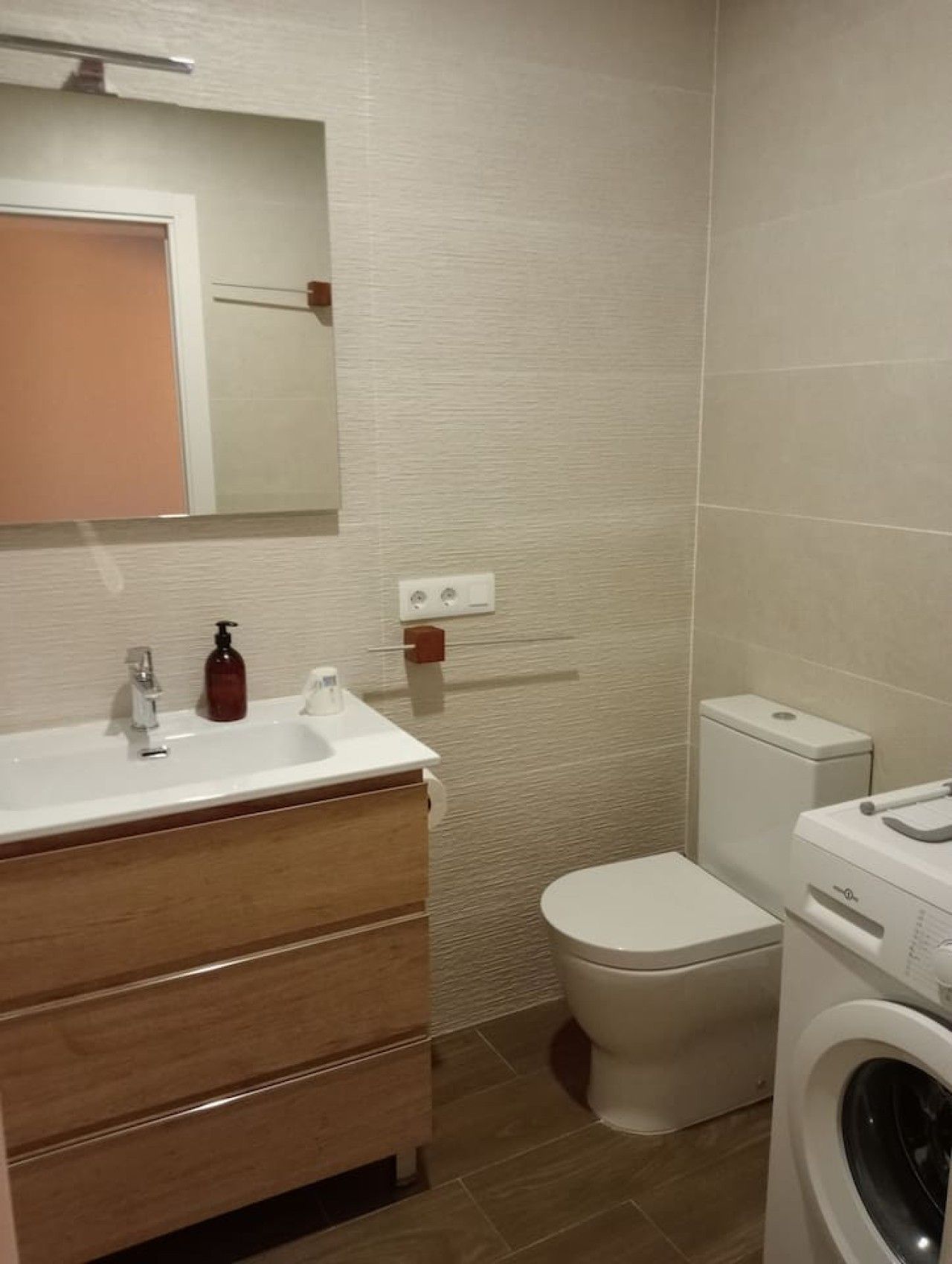 Une salle de bain équipée d’un lavabo, d’un miroir, de toilettes et d’un lave-linge.