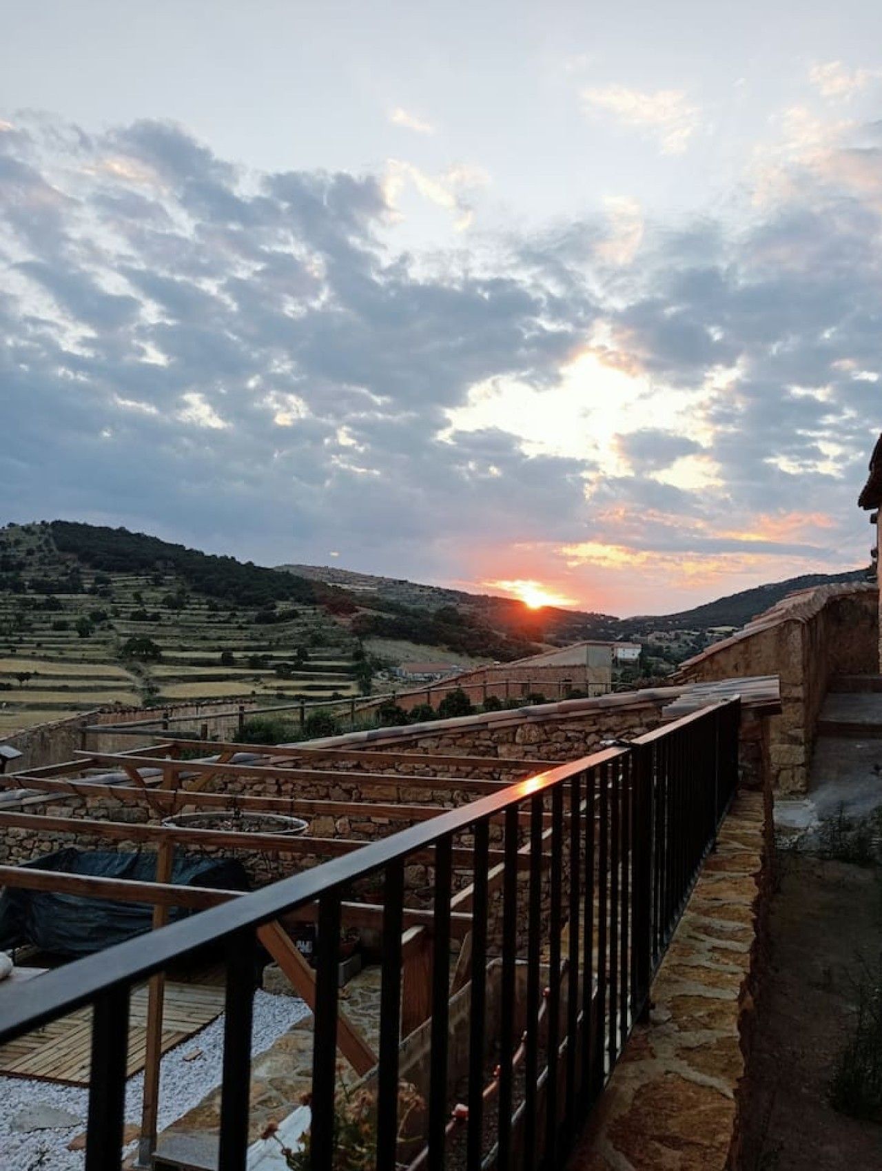 A terrace with stone railings overlooking terraced fields and a sunset.