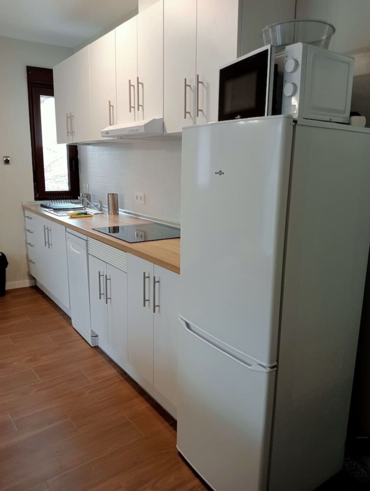Eine Küche mit weißen Schränken, einer Mikrowelle und einem Kühlschrank.