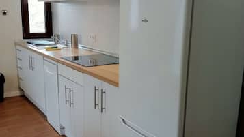 Eine Küche mit weißen Schränken, einer Mikrowelle und einem Kühlschrank.