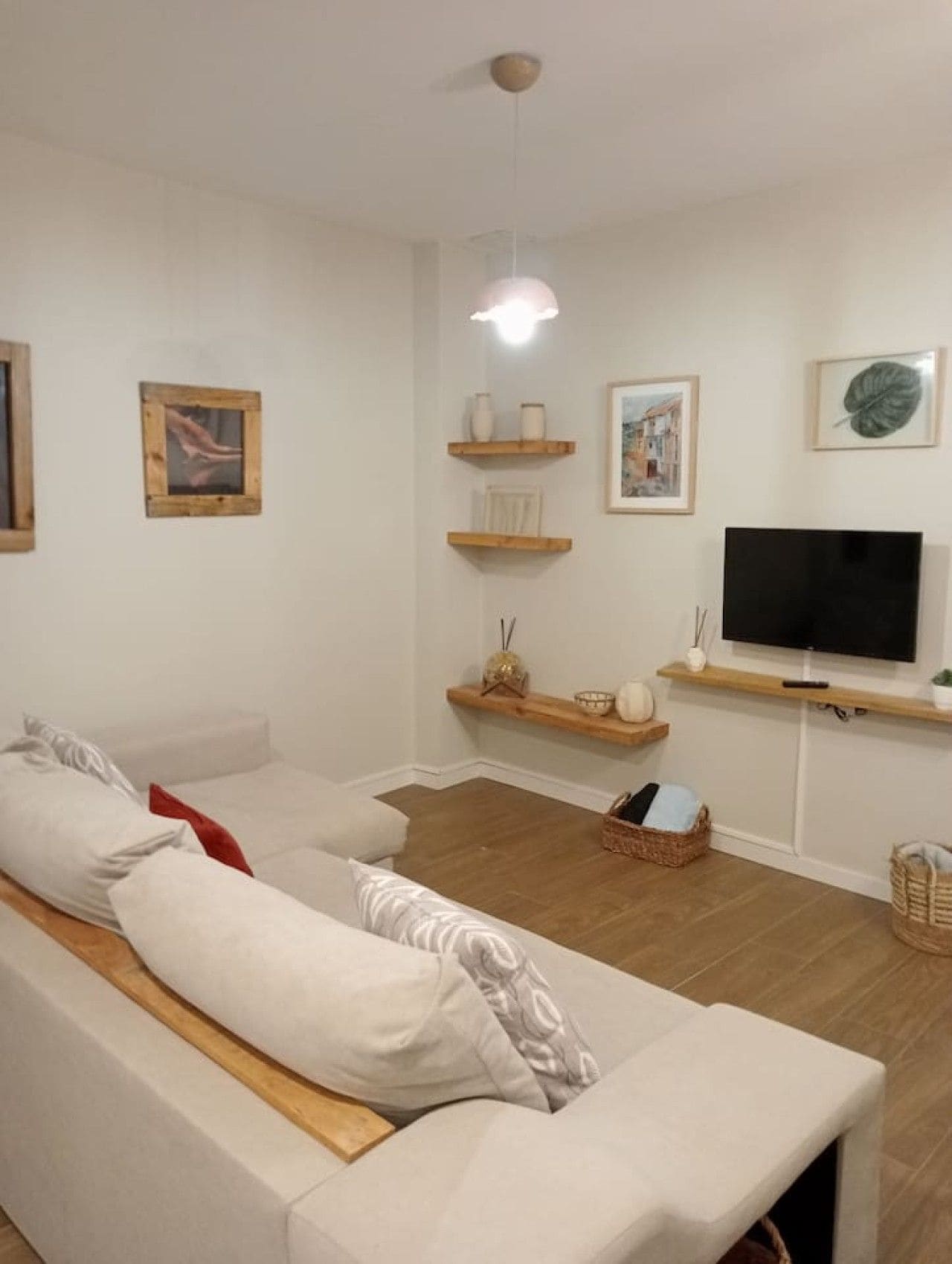 Ein Wohnzimmer mit einer Couch, einem Fernseher, Regalen und Kunstwerken.
