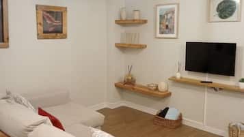 Ein Wohnzimmer mit einer Couch, einem Fernseher, Regalen und Kunstwerken.