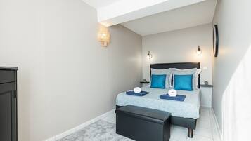 Une chambre à coucher comprenant un lit, des tables de chevet, un banc et une armoire.