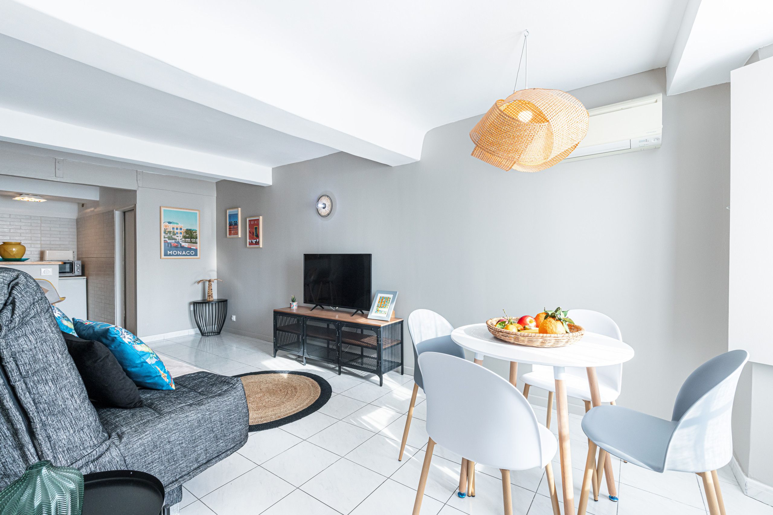 Un salon moderne comprenant un canapé, une table à manger avec des chaises, un téléviseur et une horloge murale.