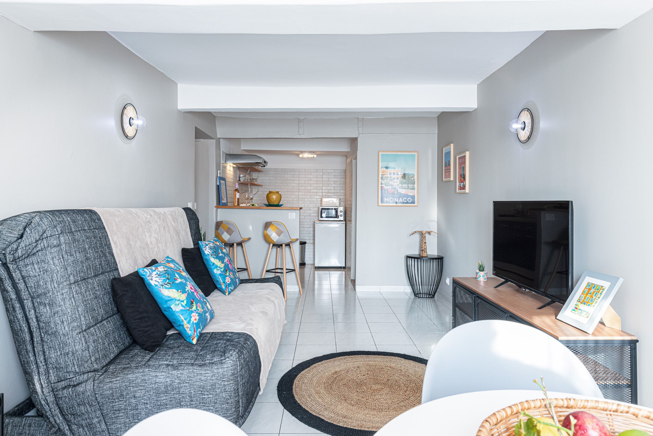 Un salon moderne avec un canapé gris, un téléviseur à écran plat et un coin repas comprenant une table et des chaises.