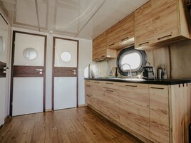 Una cucina compatta con mobili in legno, un oblò tondo sopra il lavello e una porta con una finestra circolare.