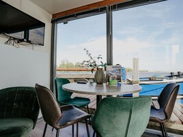 Una stanza con un'ampia finestra, un tavolo rotondo e sedie verdi.