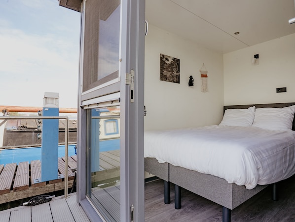 Quarto com cama, janela, luminária na parede e um quadro.