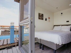 Una camera da letto con un letto, una finestra, una lampada a parete e un quadro.