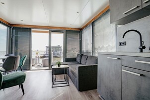 Una cucina moderna con forno integrato, un divano grigio e un'area pranzo con tavolo e sedie.
