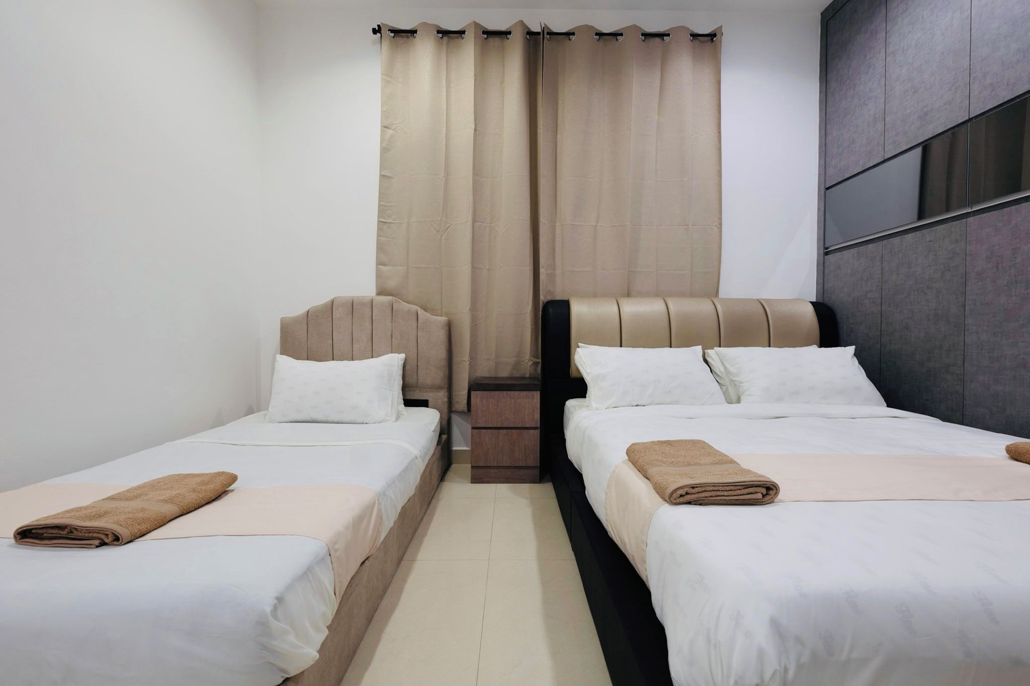 Une chambre d’hôtel avec deux lits, une table de chevet et une fenêtre avec des rideaux.