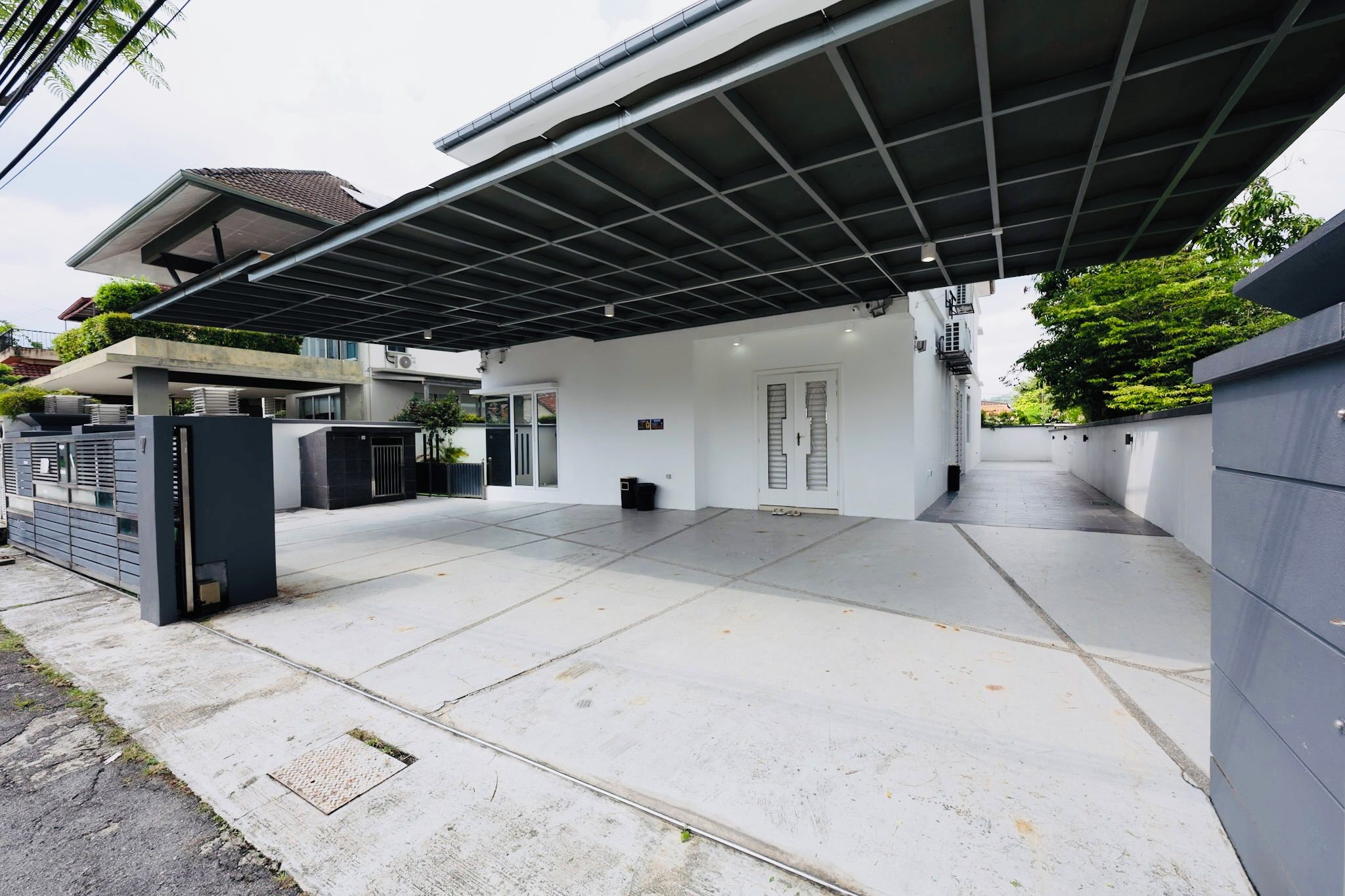 A modern residential property with a covered driveway, a gated entrance, and a flat roof.