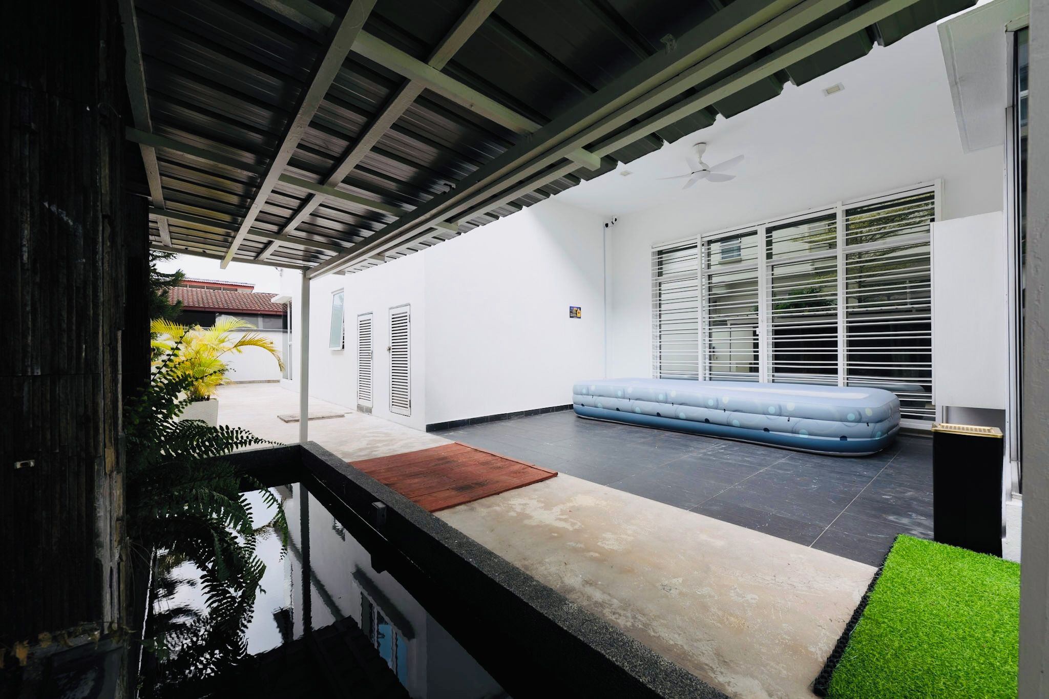 A modern outdoor living area with a pool, a blue sofa, and a covered patio.