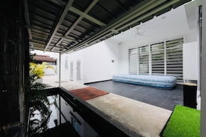 A modern outdoor living area with a pool, a blue sofa, and a covered patio. - PJ Old Town 6KM Mid Valley 35Pax9Car (Petaling Jaya)