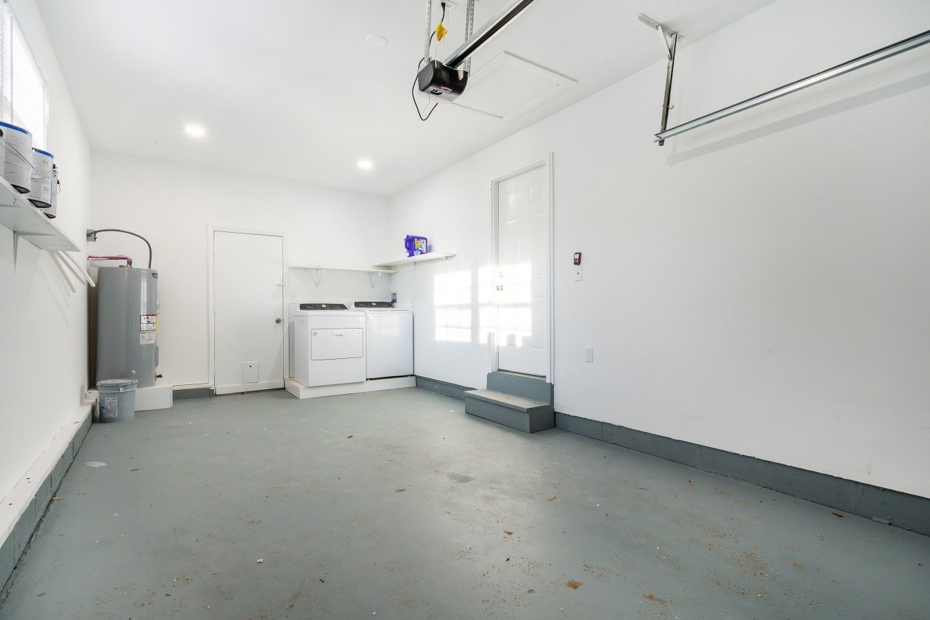 Una habitación limpia y vacía con lavadora, calentador de agua y un proyector montado en el techo.