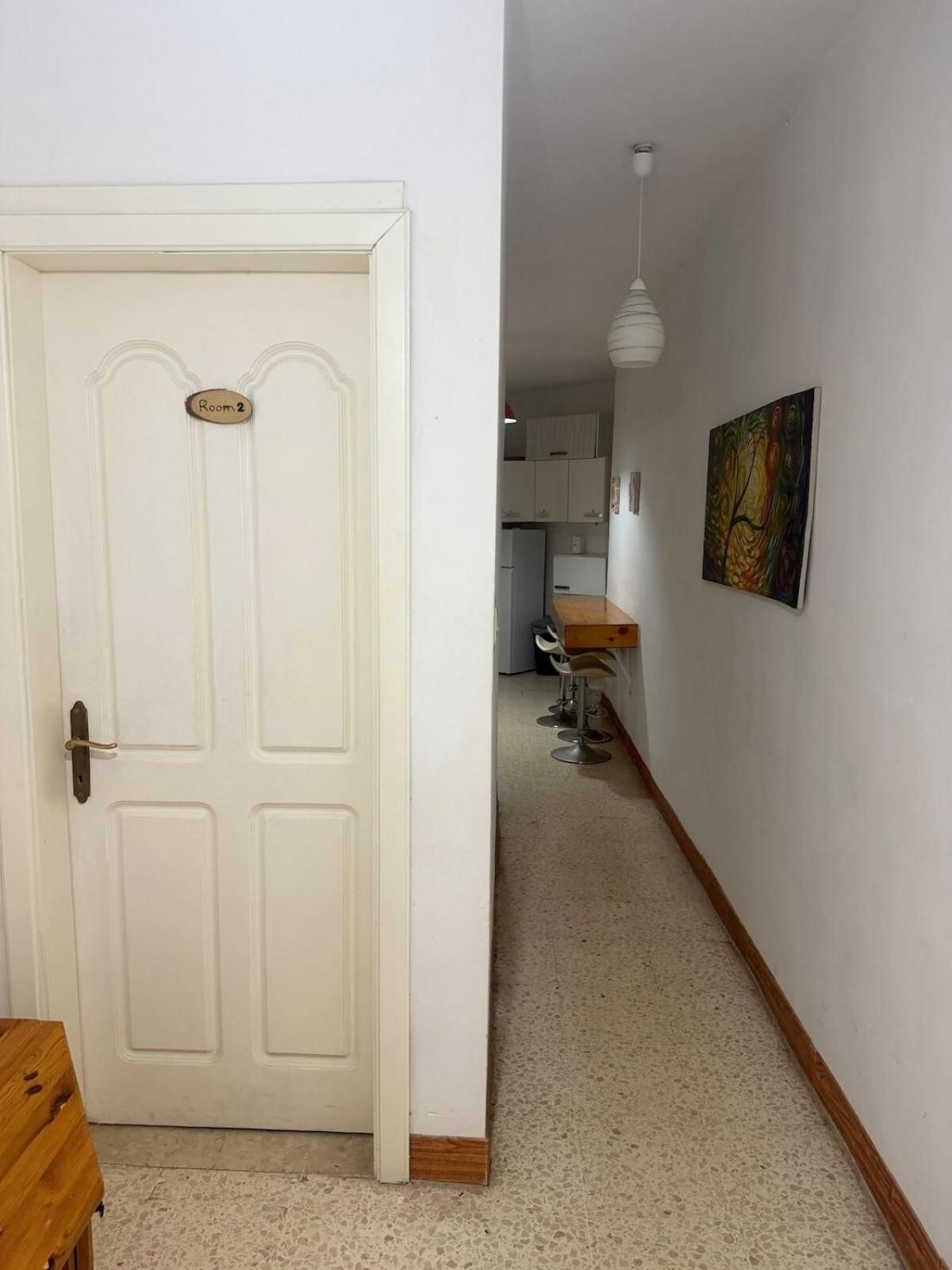 Un couloir mène à une pièce dont la porte blanche est marquée du numéro « Salle 2 ».