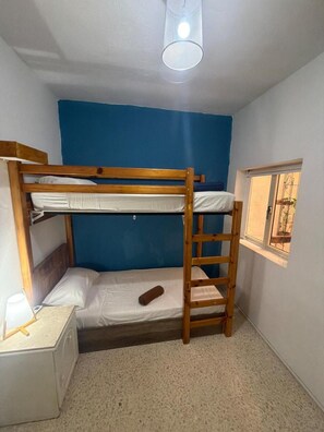 Ein Schlafraum mit Etagenbetten, Fenster und Schreibtisch.