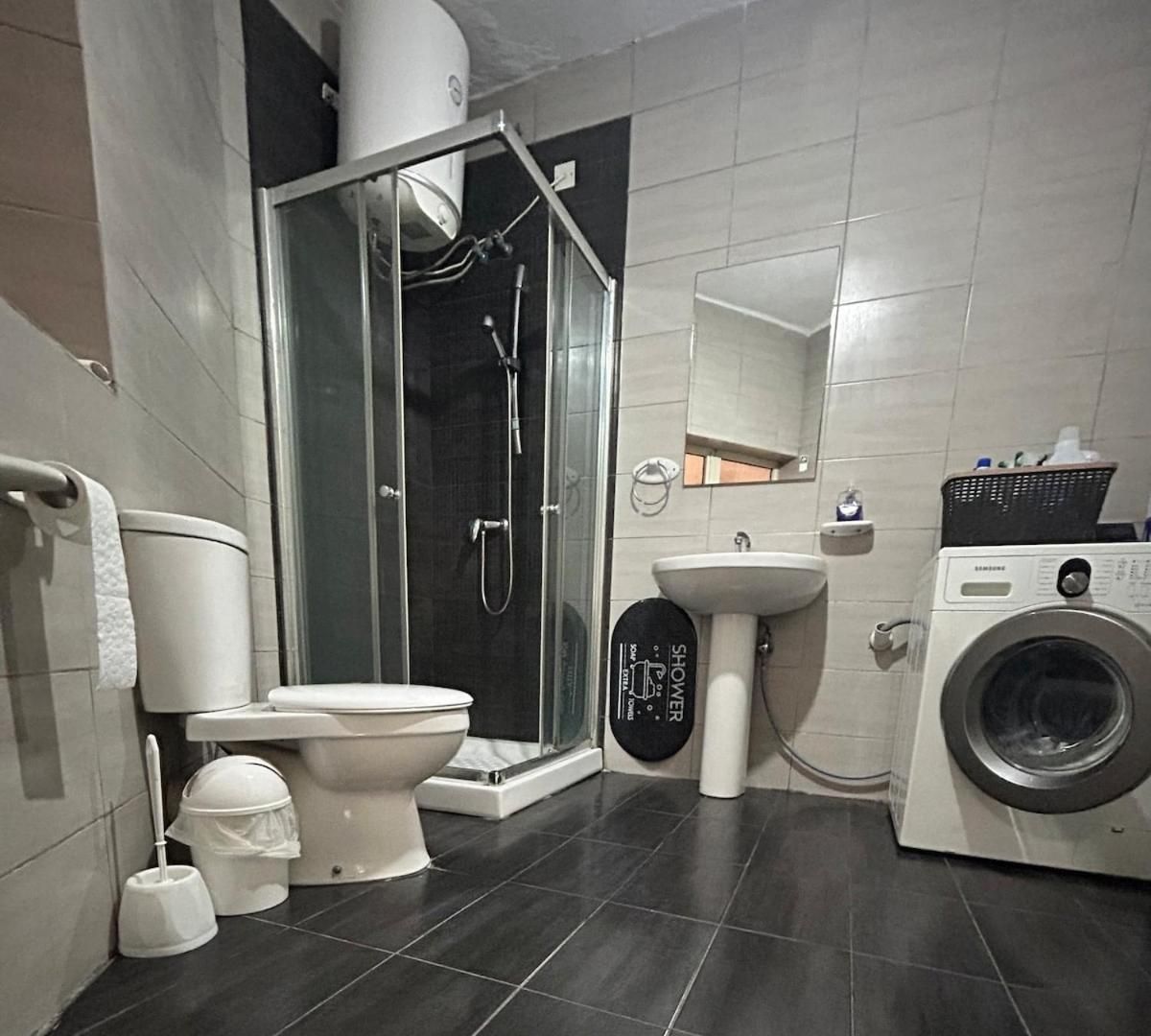 Une salle de bain moderne équipée de toilettes, d’une douche, d’un lavabo et d’un lave-linge.