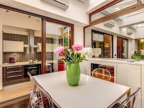 Een moderne keuken met een eethoek, met een groot raam, een vaas met bloemen en een eettafel.