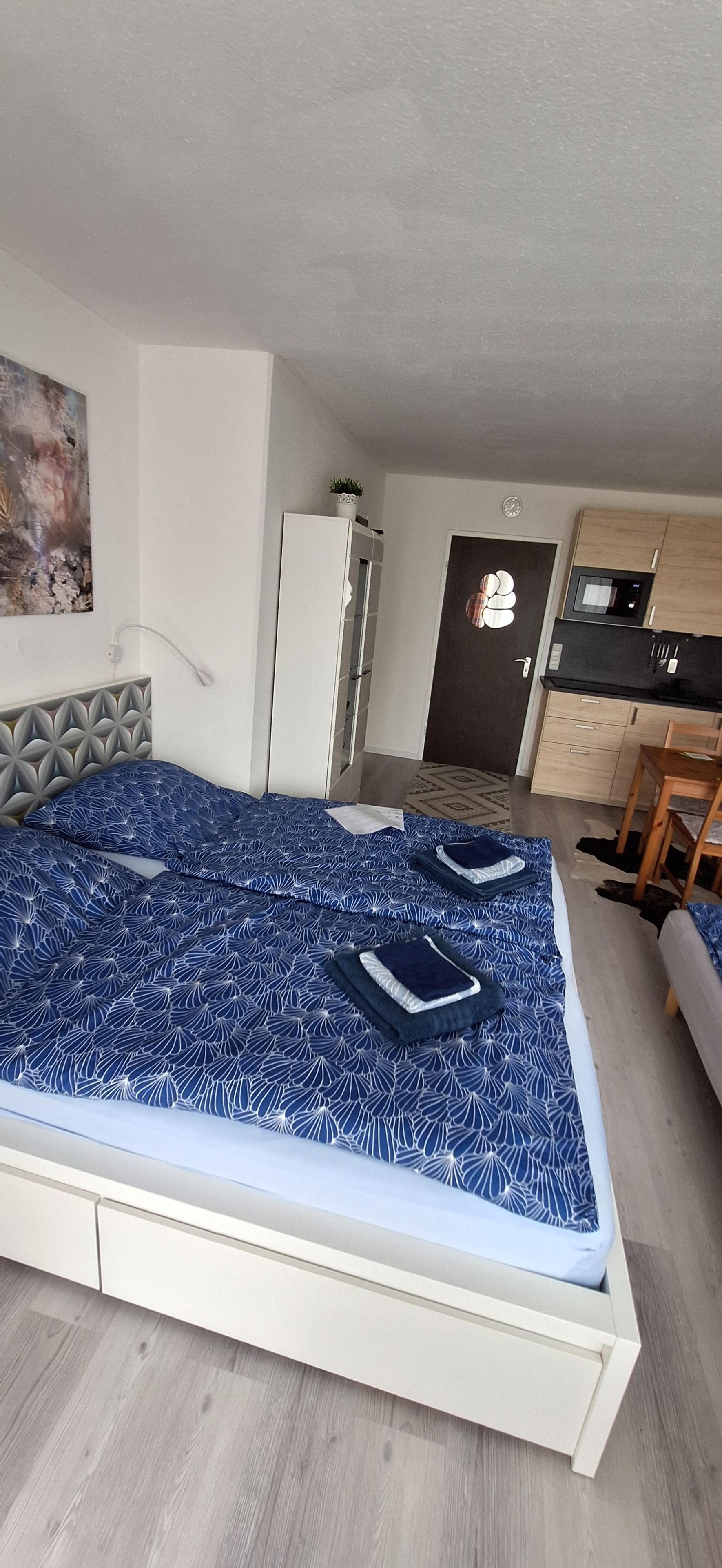 Ein Schlafzimmer mit Bett, Kleiderschrank, Schreibtisch und einer Küchenzeile.