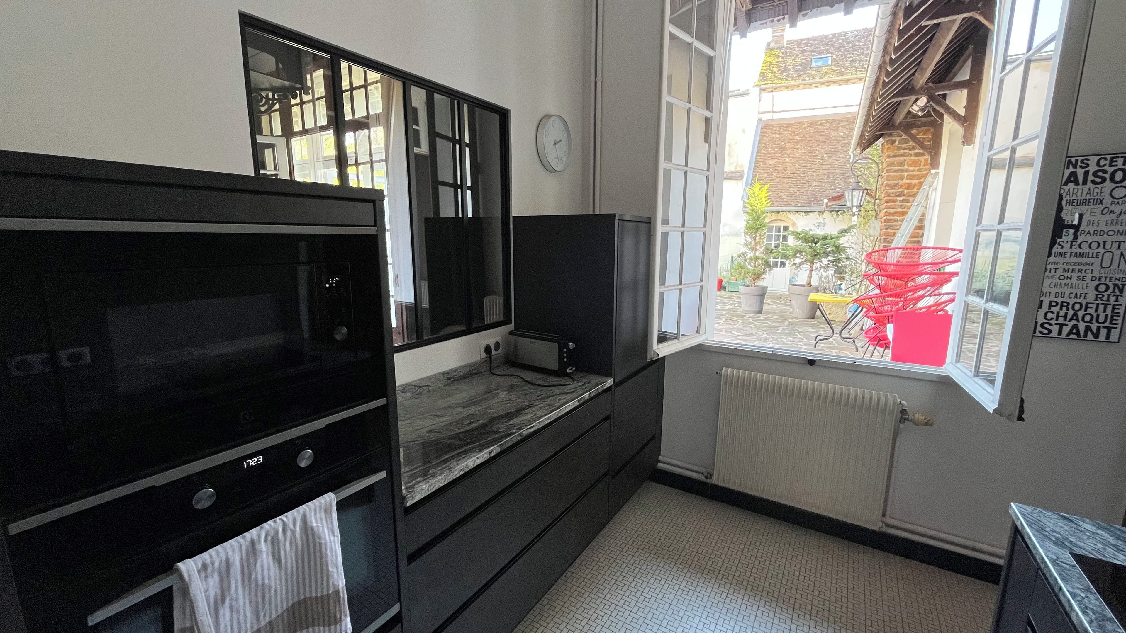 Een keuken met een inbouwoven, een magnetron en een raam met uitzicht.