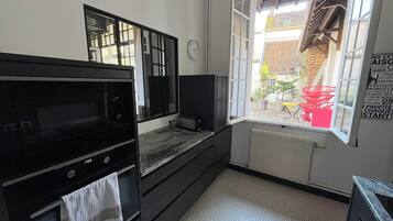 Een keuken met een inbouwoven, een magnetron en een raam met uitzicht.